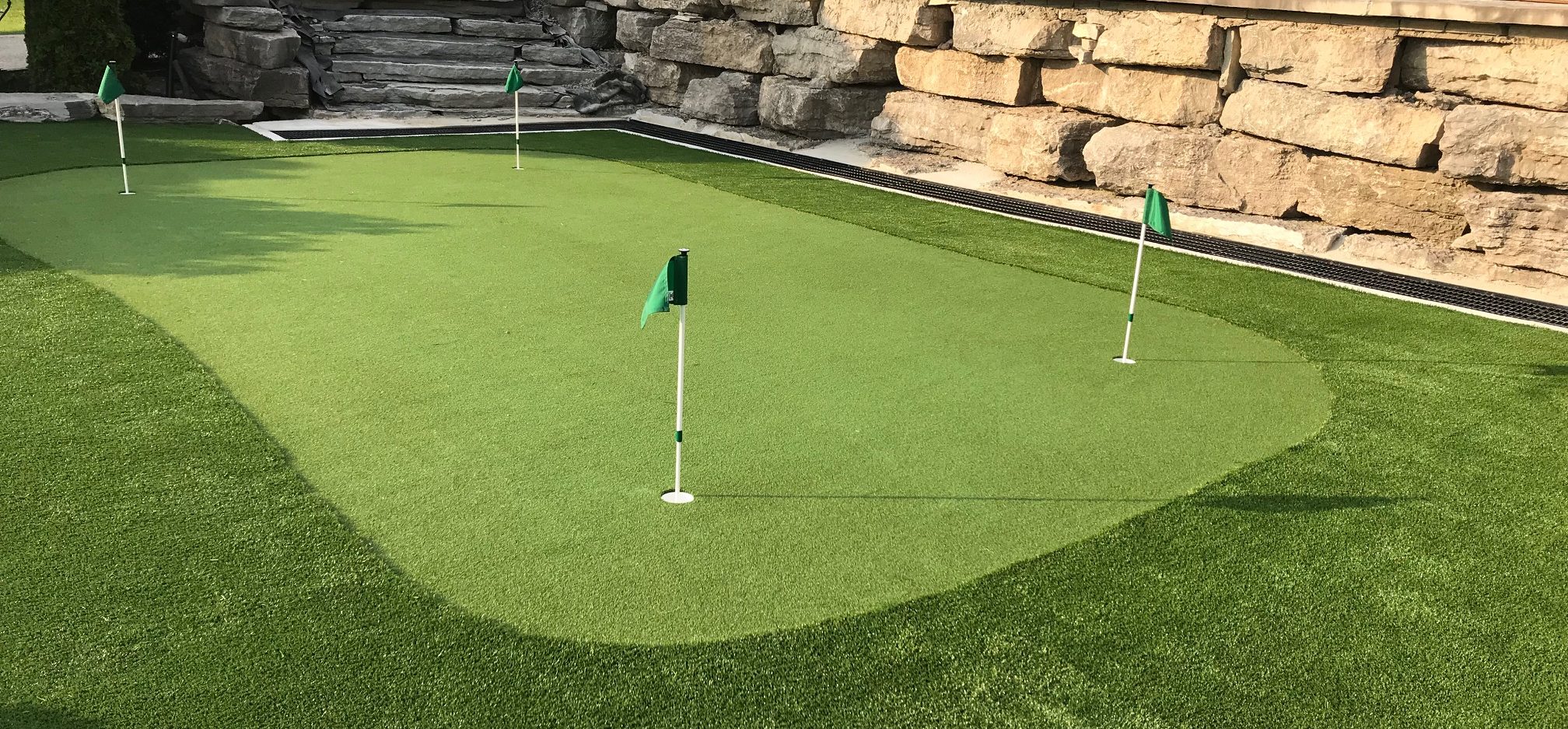 Stunning golf green and fringe turf with large Armour stone wall